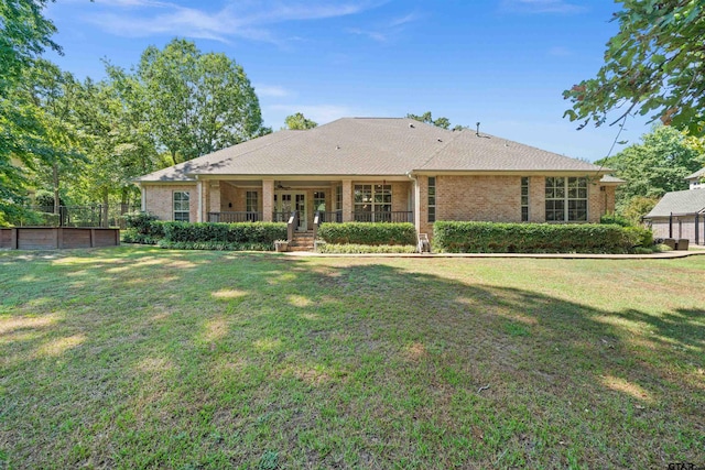 back of property featuring covered porch and a lawn