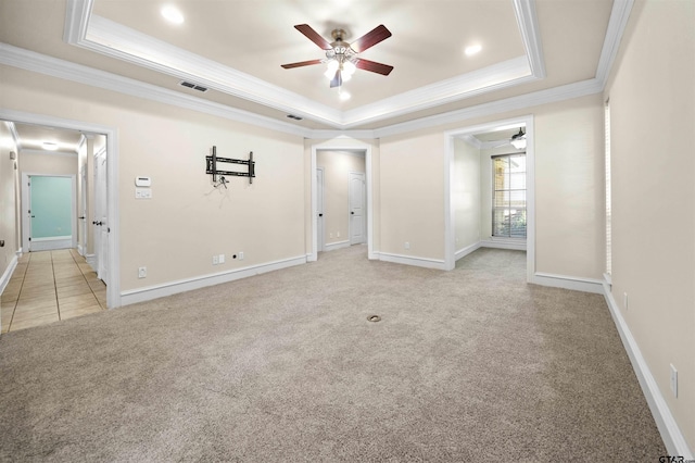 spare room with ornamental molding, light colored carpet, ceiling fan, and a tray ceiling