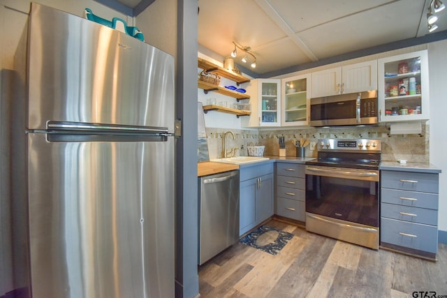 21171 Sand Jack Rd, Larue, TX 75770 - kitchen featuring appliances with stainless steel finishes, a sink, tasteful backsplash, light wood finished floors, and open shelves