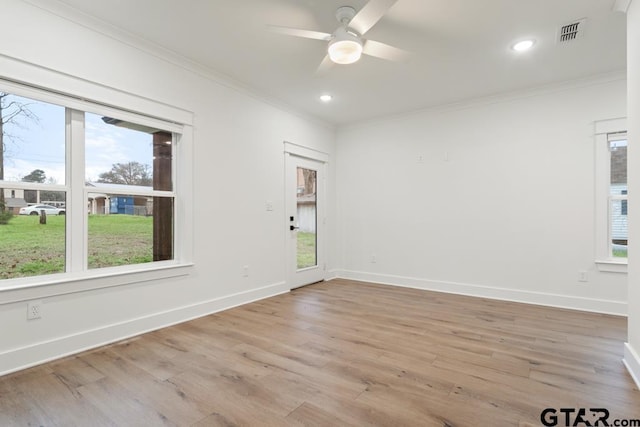 spare room featuring crown molding, plenty of natural light, and light hardwood / wood-style flooring