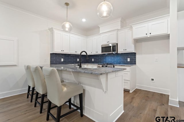 kitchen with decorative light fixtures, light stone countertops, kitchen peninsula, and white cabinets