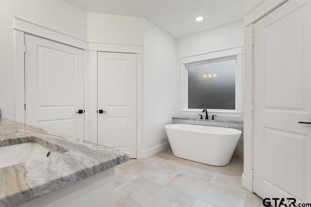 bathroom featuring vanity, tile patterned flooring, and a washtub