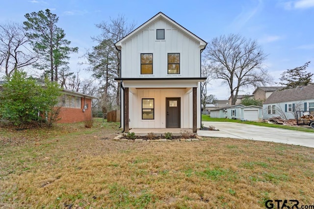 modern farmhouse style home featuring covered porch and a front lawn