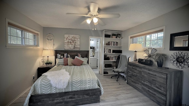 bedroom featuring ceiling fan, ensuite bath, light wood-type flooring, and a textured ceiling