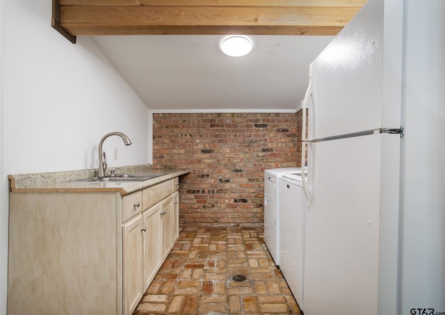 laundry area featuring brick floor, brick wall, and a sink