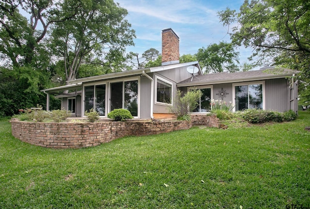 rear view of house featuring a lawn and a chimney