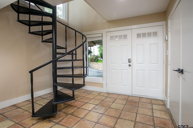 foyer entrance with baseboards, stairway, and stone tile flooring