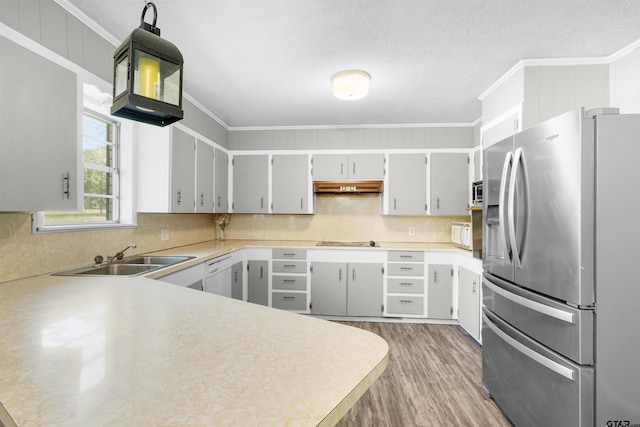 kitchen with a sink, ornamental molding, under cabinet range hood, and stainless steel appliances