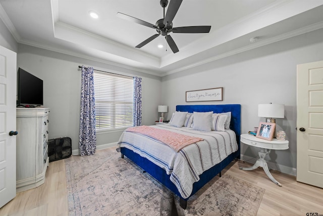 bedroom with crown molding, hardwood / wood-style flooring, ceiling fan, and a raised ceiling