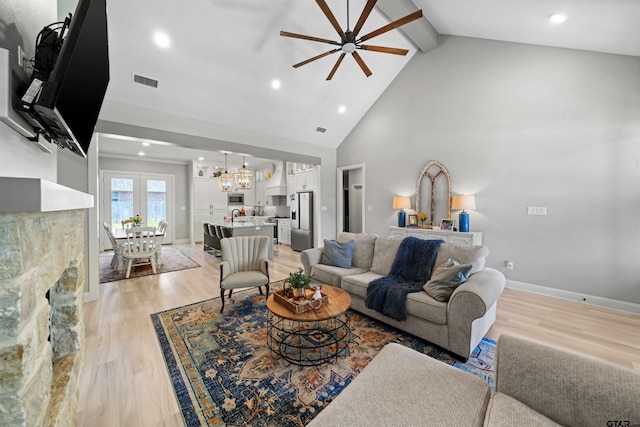 living room with high vaulted ceiling, beamed ceiling, ceiling fan with notable chandelier, and light hardwood / wood-style flooring