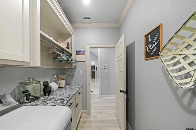 washroom featuring light hardwood / wood-style flooring, cabinets, crown molding, and washing machine and clothes dryer