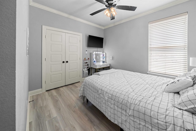 bedroom featuring ornamental molding, light wood-type flooring, ceiling fan, and a closet