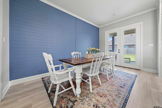 dining space featuring light wood-type flooring, french doors, and ornamental molding