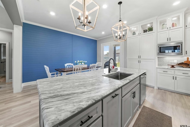 kitchen with white cabinets, sink, an island with sink, backsplash, and appliances with stainless steel finishes