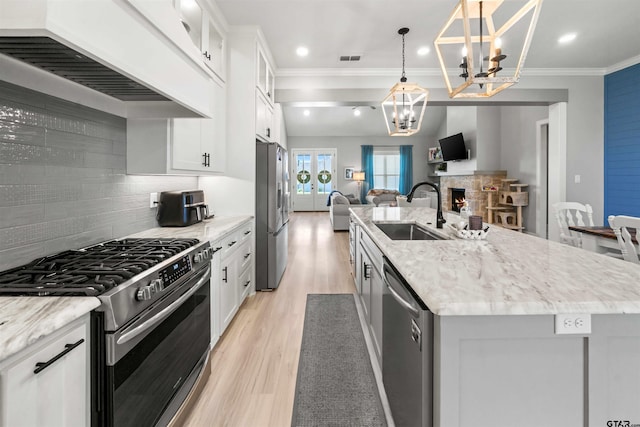 kitchen featuring tasteful backsplash, white cabinetry, appliances with stainless steel finishes, pendant lighting, and sink