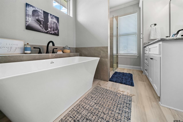 bathroom with ornamental molding, hardwood / wood-style floors, a washtub, and vanity