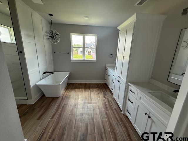 14533 Woodland Creek Dr, Tyler, TX 75706 - full bathroom featuring two vanities, a freestanding bath, and wood finished floors