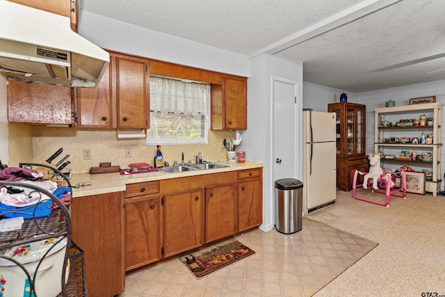 552 W State Highway 7, Crockett, TX 75835 - kitchen with freestanding refrigerator, a sink, under cabinet range hood, light countertops, and brown cabinetry