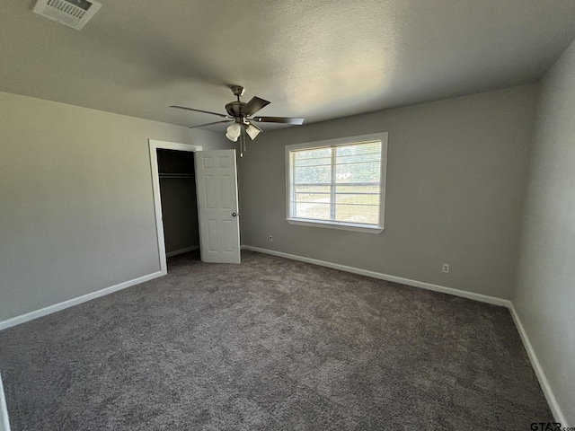 unfurnished bedroom featuring ceiling fan, a closet, and dark colored carpet