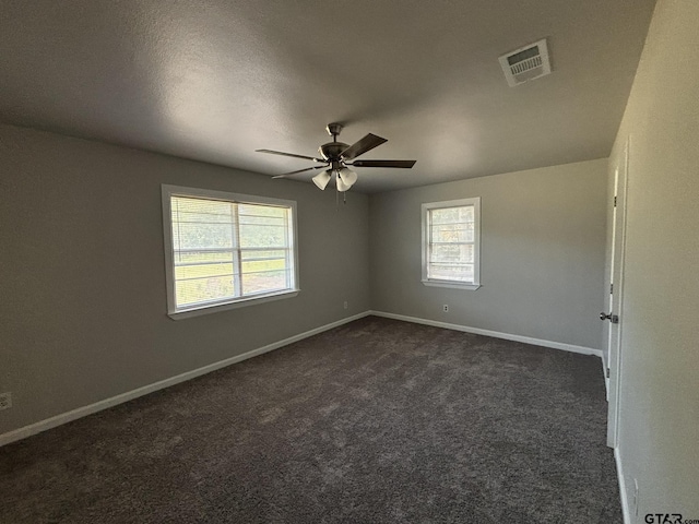 empty room with ceiling fan, a textured ceiling, and dark colored carpet