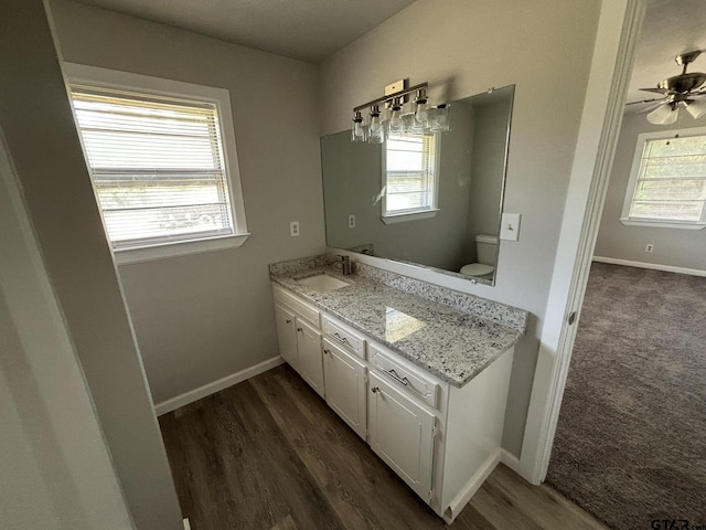 bathroom with hardwood / wood-style flooring, toilet, vanity, and ceiling fan