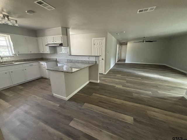 kitchen featuring backsplash, kitchen peninsula, sink, white cabinets, and dark hardwood / wood-style flooring