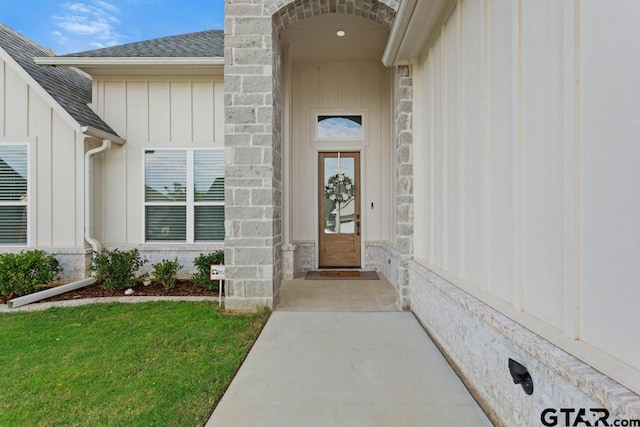 4188 Palo Pinto Creek Cir, Tyler, TX 75703 - view of exterior entry with board and batten siding, a shingled roof, a yard, and stone siding