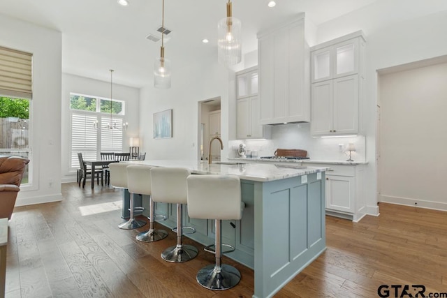 4188 Palo Pinto Creek Cir, Tyler, TX 75703 - kitchen featuring white cabinets, light wood finished floors, a kitchen island with sink, recessed lighting, and a kitchen bar