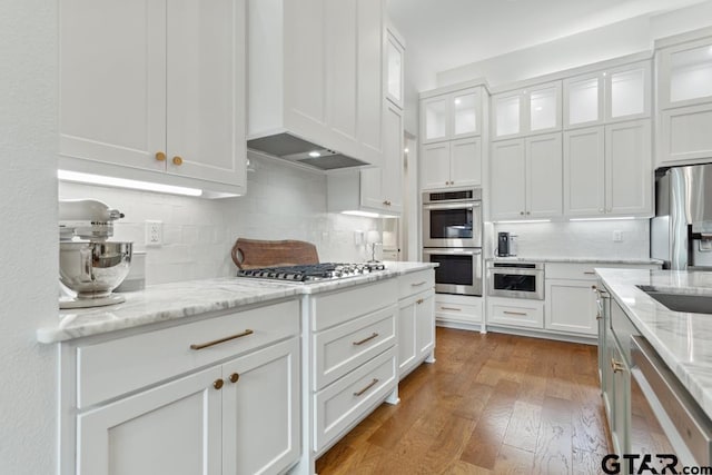 4188 Palo Pinto Creek Cir, Tyler, TX 75703 - kitchen featuring white cabinetry, stainless steel appliances, tasteful backsplash, wood finished floors, and glass insert cabinets