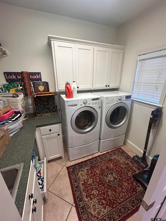 laundry area featuring cabinets, light tile patterned floors, washing machine and clothes dryer, and sink