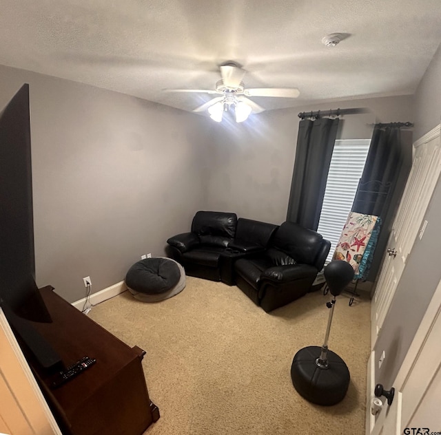 living room featuring ceiling fan, a textured ceiling, and carpet