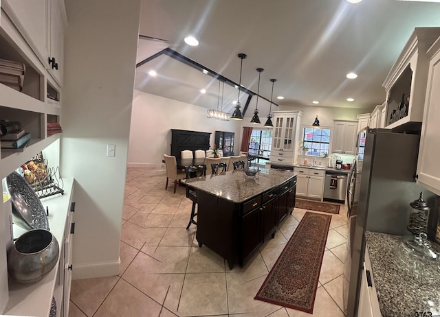 kitchen featuring a kitchen island, white cabinetry, appliances with stainless steel finishes, pendant lighting, and a kitchen breakfast bar