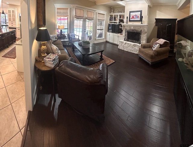 living room with a stone fireplace, light hardwood / wood-style flooring, and crown molding