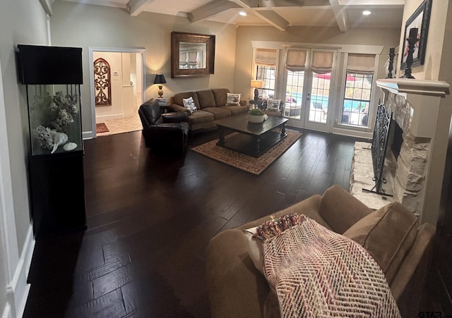 living room with hardwood / wood-style floors, beamed ceiling, a stone fireplace, and french doors