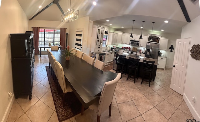 tiled dining room with sink, a chandelier, and vaulted ceiling