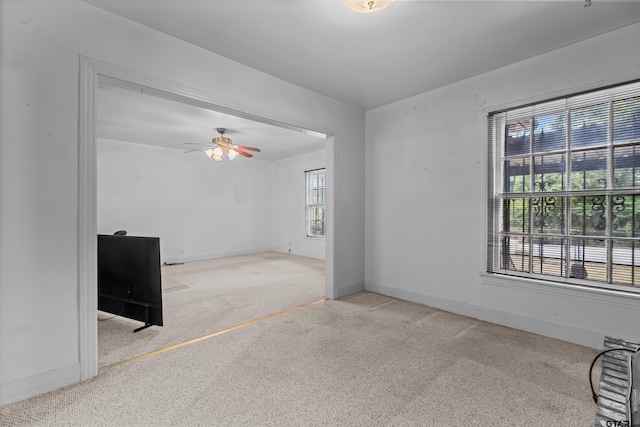 unfurnished living room with a ceiling fan, light carpet, and baseboards