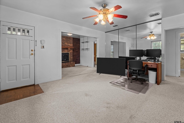 office area with a brick fireplace, visible vents, and light colored carpet