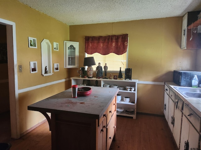 kitchen with dark wood-type flooring, sink, a textured ceiling, and white cabinets
