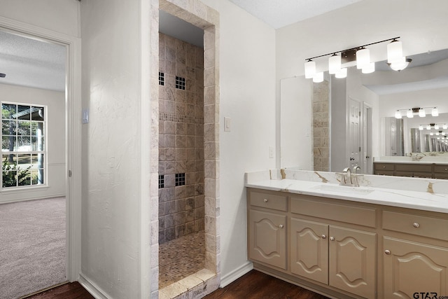 bathroom featuring hardwood / wood-style floors, vanity, a textured ceiling, and tiled shower