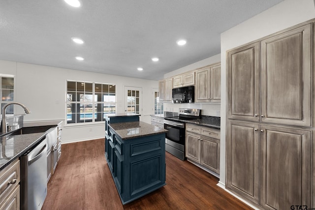 kitchen featuring dark stone counters, a center island with sink, stainless steel appliances, and sink