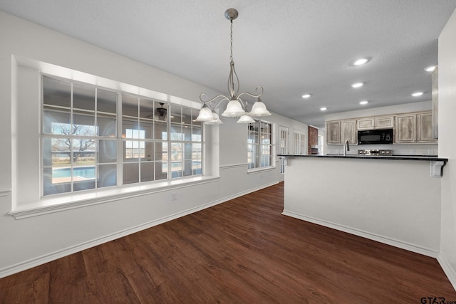 kitchen featuring dark wood-type flooring, decorative light fixtures, a textured ceiling, light brown cabinetry, and a notable chandelier