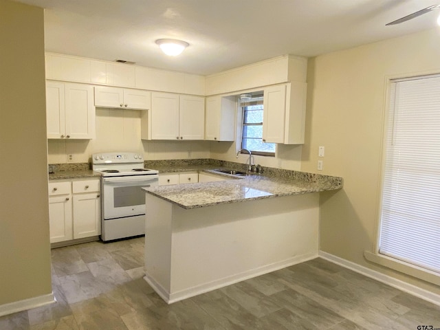 kitchen with white cabinets, sink, white electric stove, light stone countertops, and kitchen peninsula