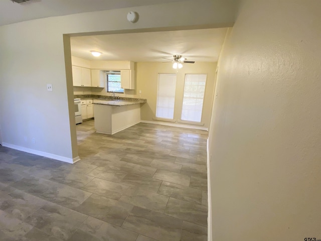 kitchen featuring kitchen peninsula, white range, ceiling fan, sink, and white cabinets