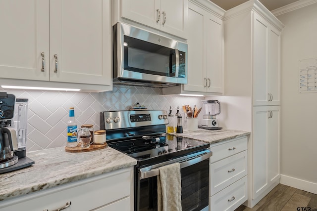 kitchen featuring light wood-type flooring, white cabinetry, appliances with stainless steel finishes, and backsplash