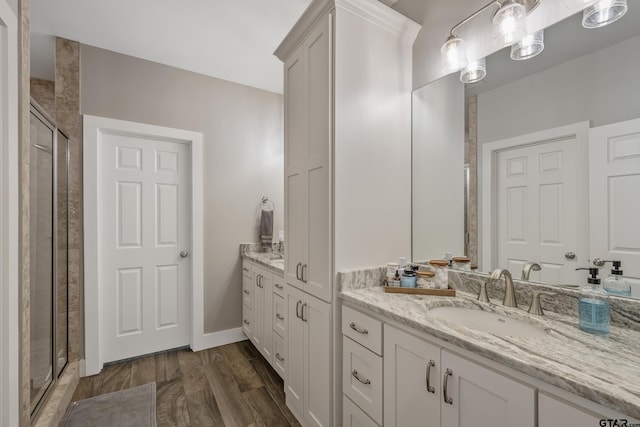 full bath with a stall shower, baseboards, wood finished floors, and vanity