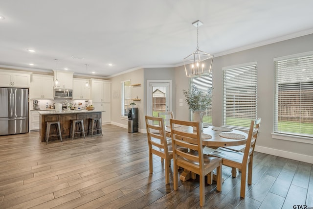 dining room featuring ornamental molding, an inviting chandelier, baseboards, and wood finished floors