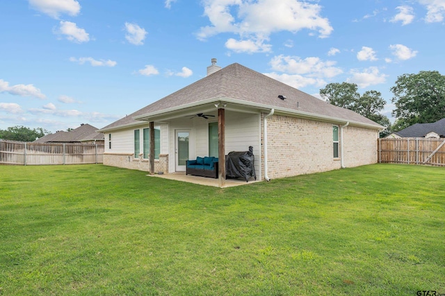 rear view of house featuring ceiling fan, a yard, brick siding, and a fenced backyard