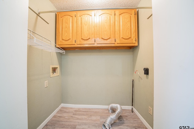 clothes washing area featuring washer hookup, cabinets, a textured ceiling, and light hardwood / wood-style floors