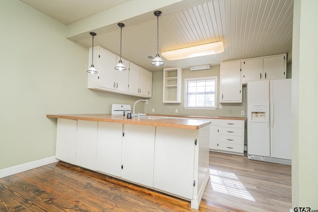 kitchen with white cabinets, decorative light fixtures, white refrigerator with ice dispenser, sink, and kitchen peninsula