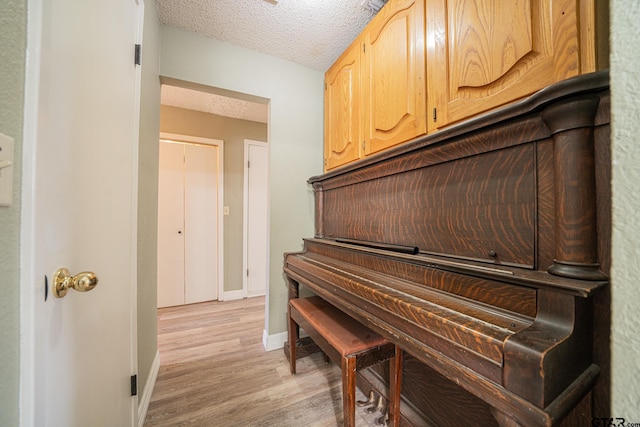 misc room with light wood-type flooring and a textured ceiling